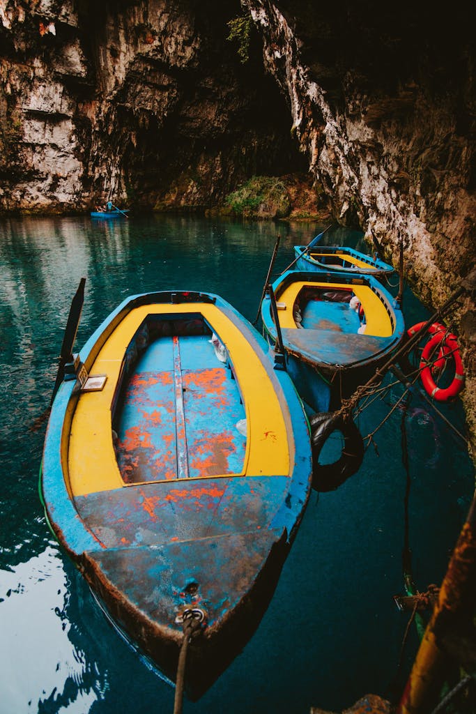 Vibrant yellow and blue boats floating on clear water in Karavomilos cave, Greece.