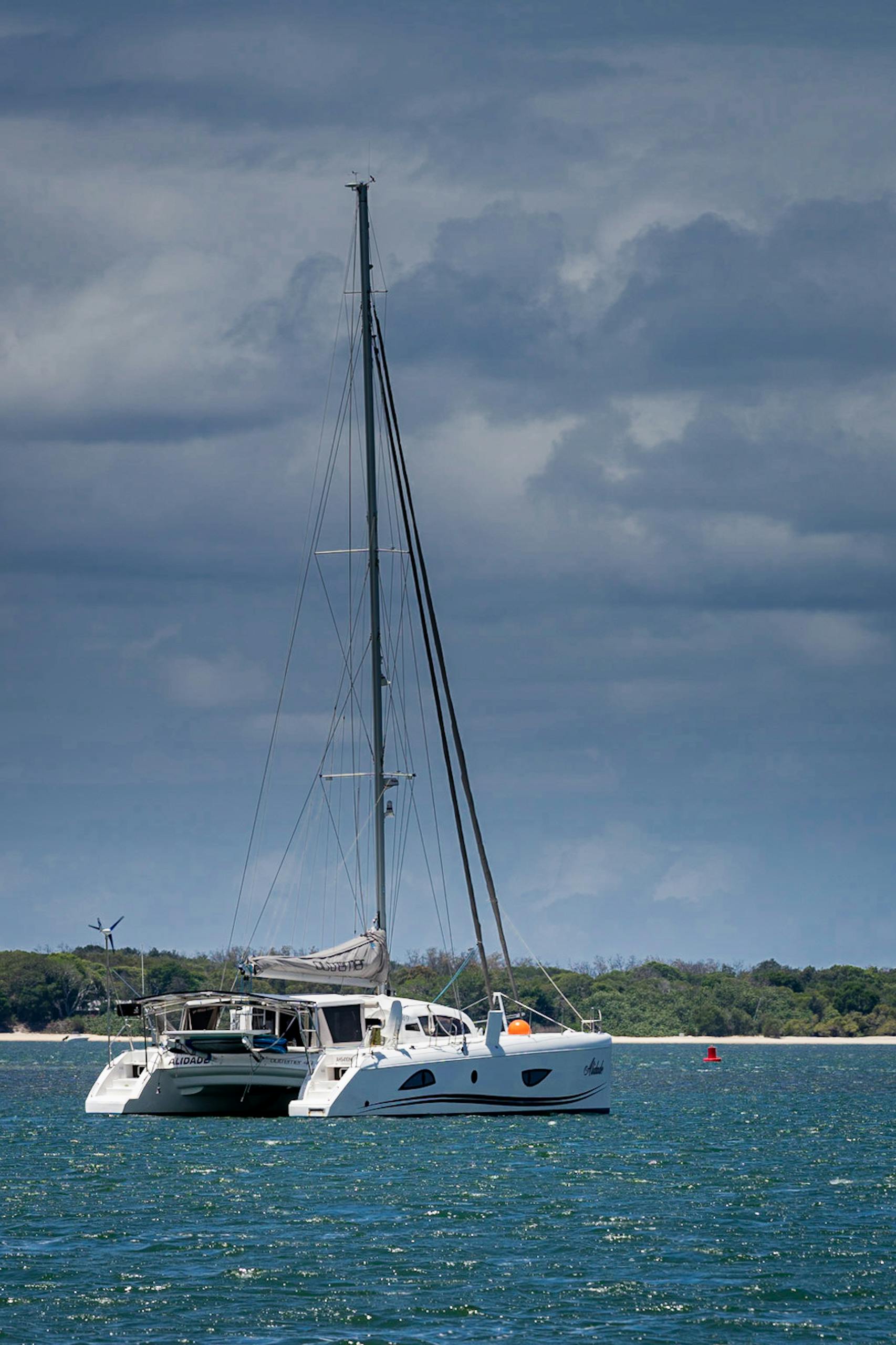 A luxurious yacht sails under a cloudy sky along the scenic Gold Coast in Queensland, Australia.