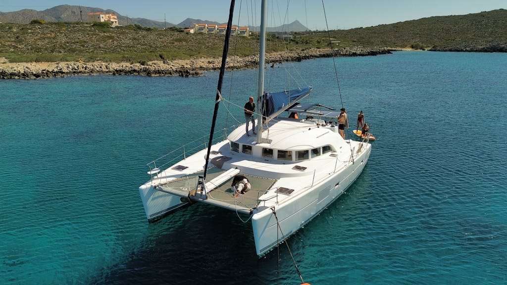 Aerial view of a catamaran with people relaxing in a serene ocean setting.