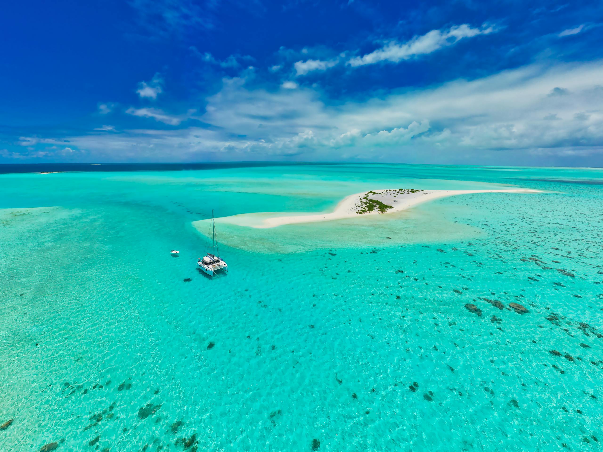 Stunning aerial view of a sailboat near a pristine sandbar in Mauritius' turquoise waters.