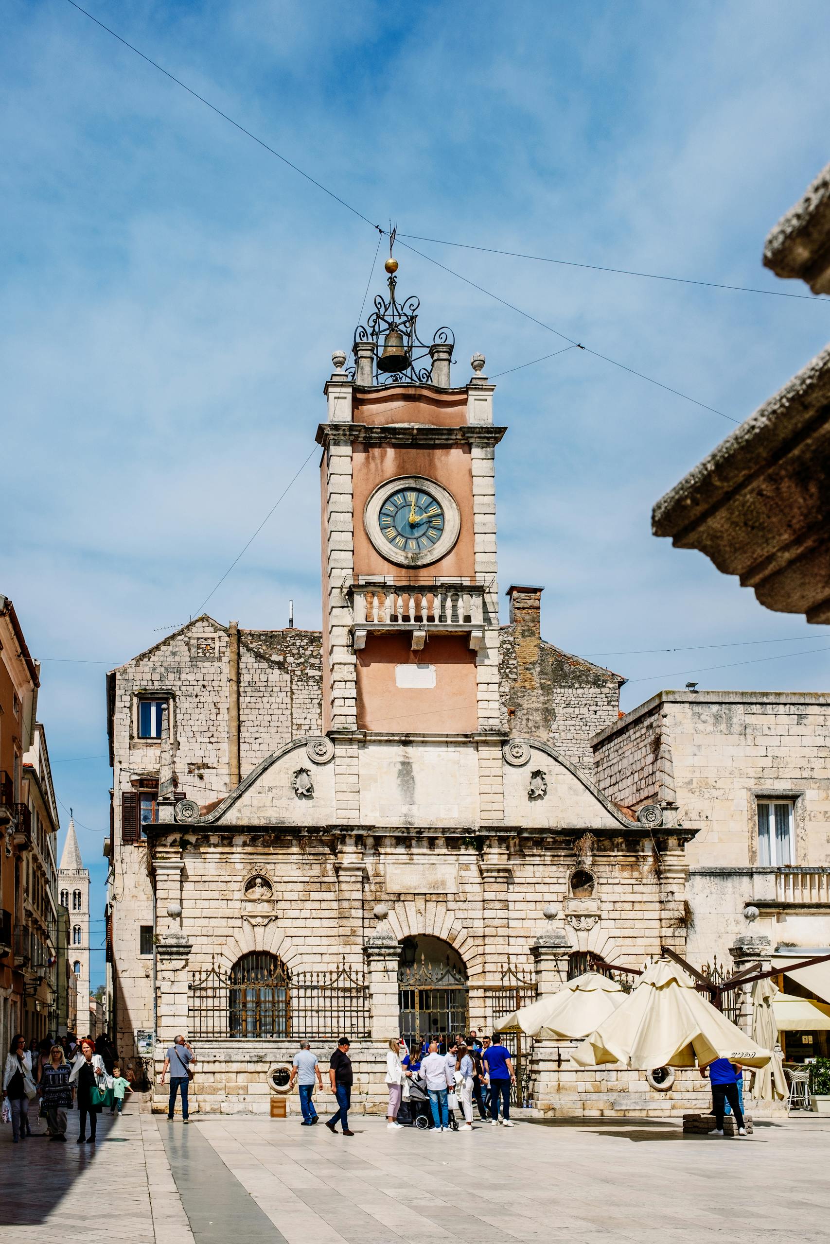 Discover the stunning architecture of a historic clock tower in a vibrant city plaza.