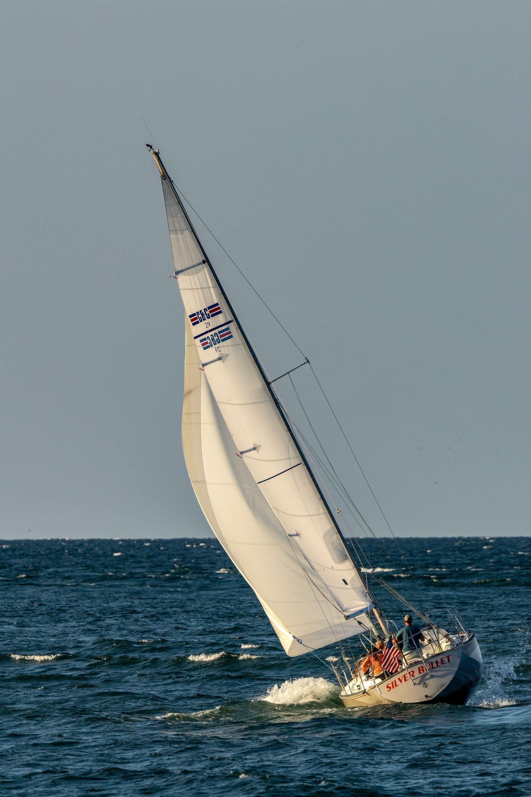 Dynamic view of a sailing boat navigating through ocean waves under a clear sky.